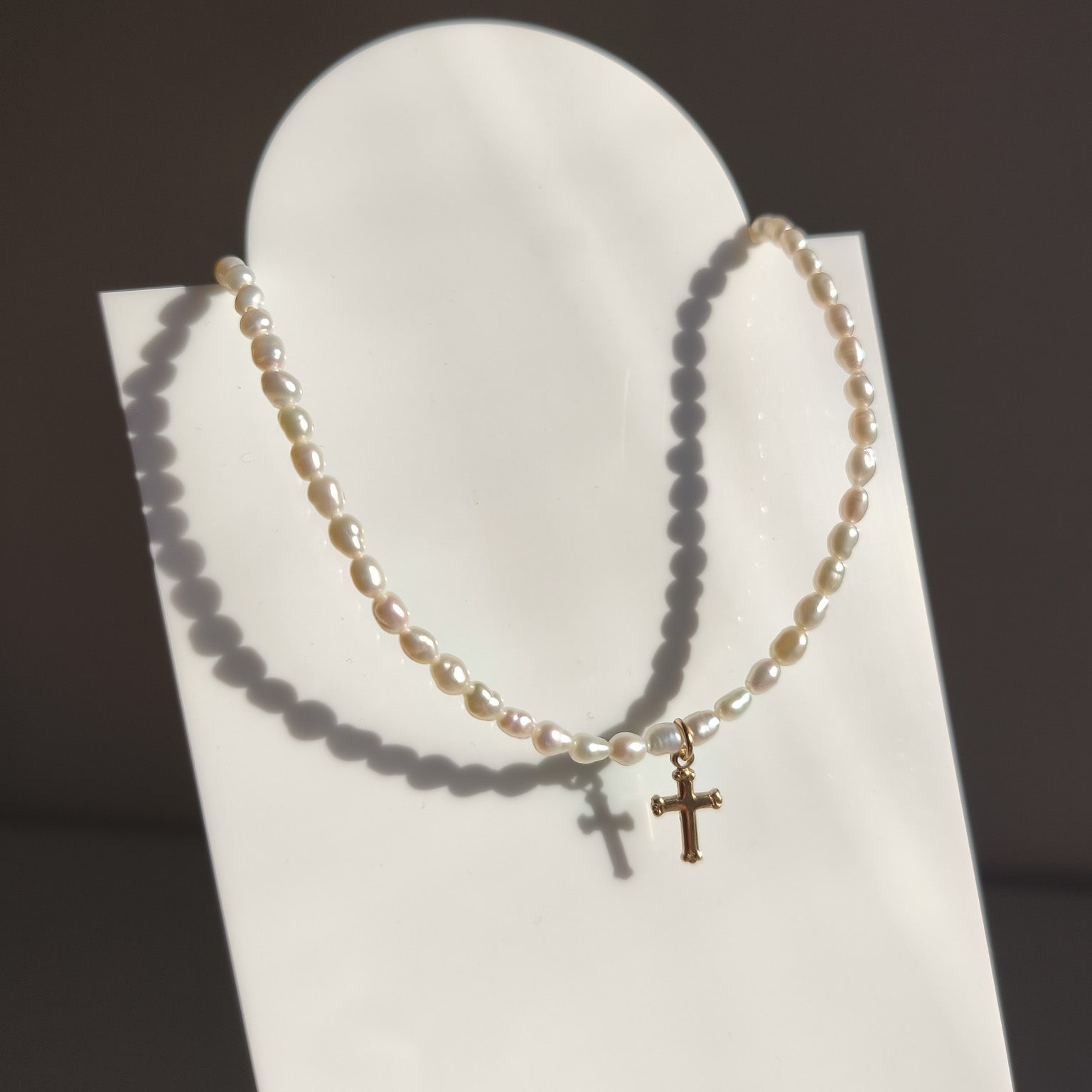 Detailní záběr na 14k Gold Filled křížek a unikátní strukturu barokních sladkovodních perel.